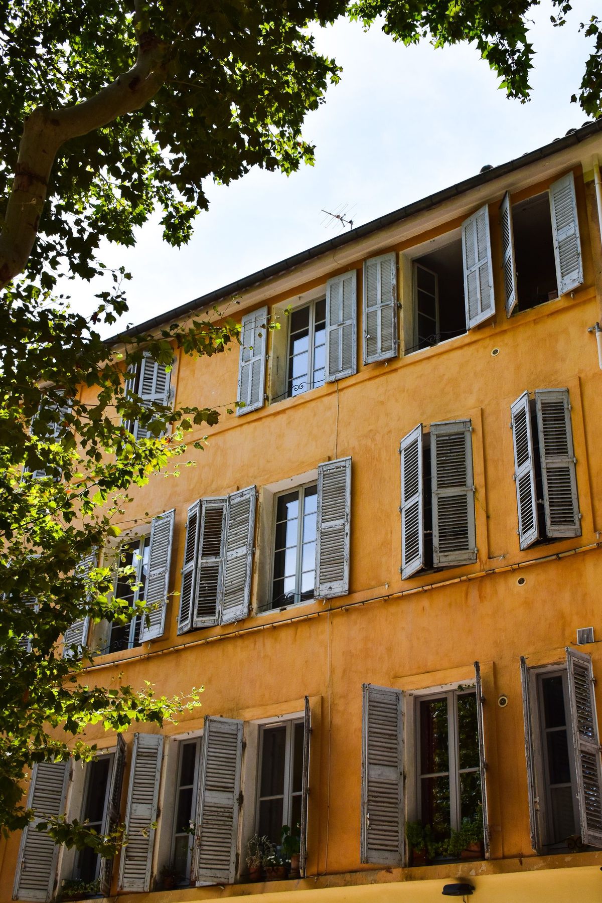 Une façade ocre aux volets ouverts, en Provence